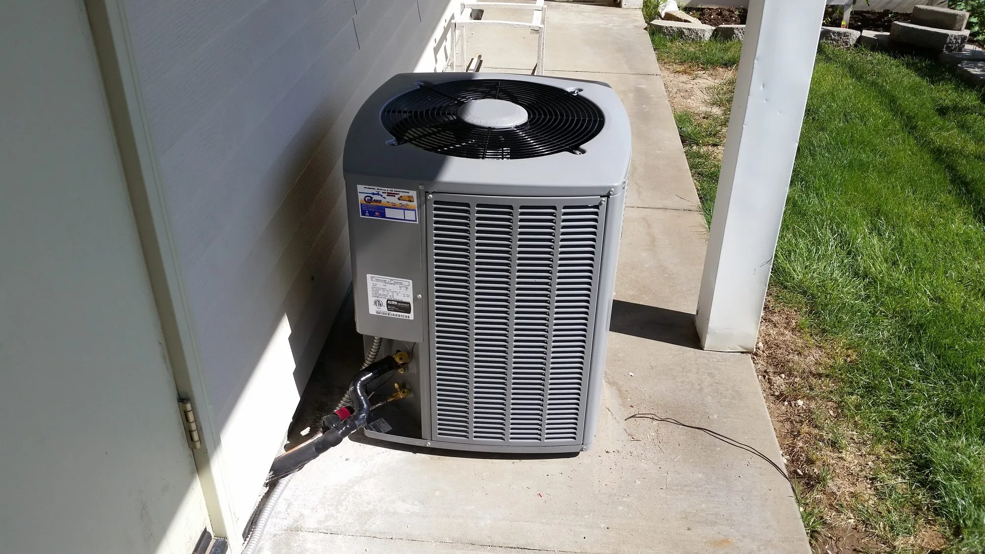An air conditioner condenser installed beside a home
