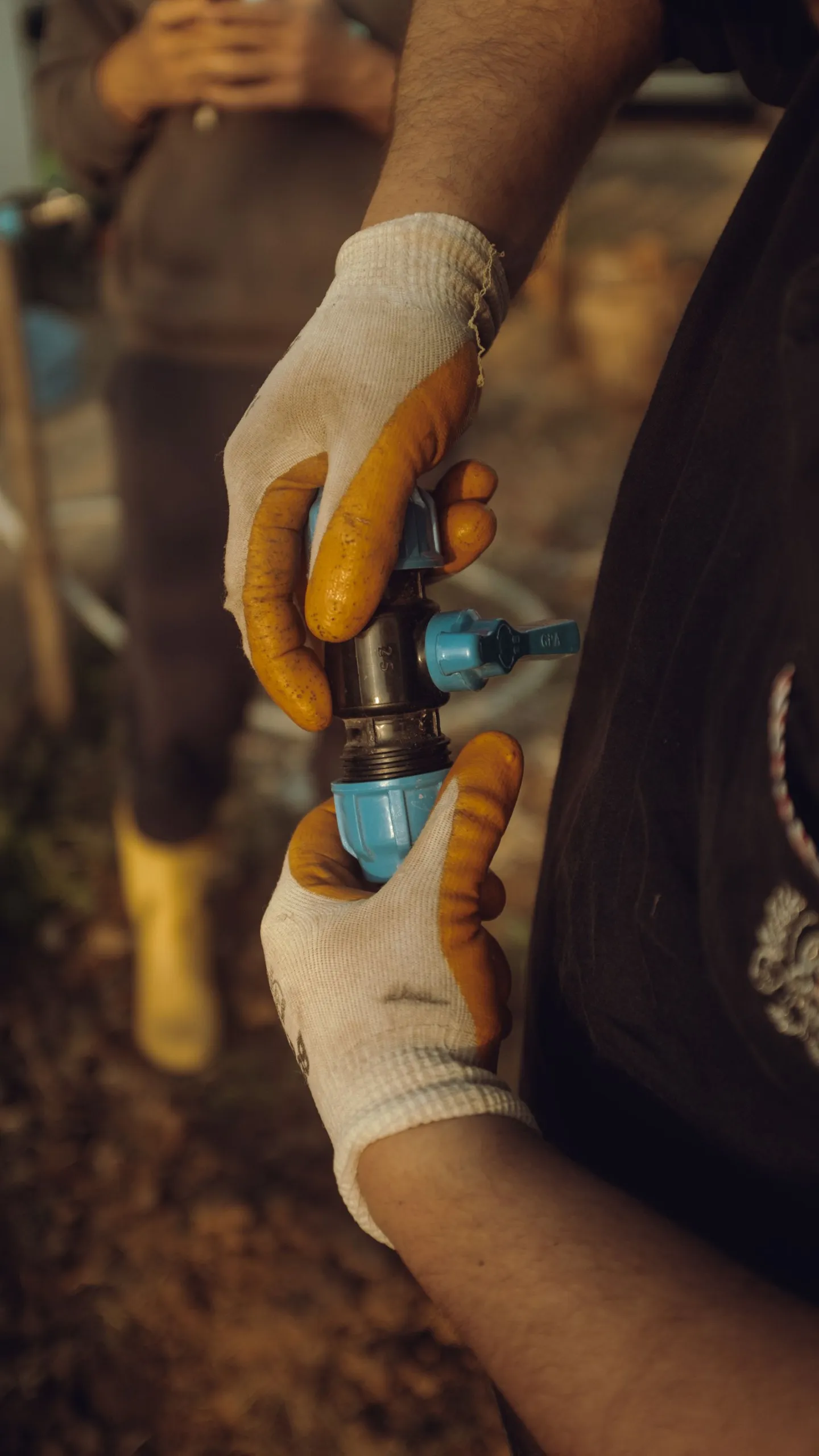 Gloved hands assembling a water pipe fitting