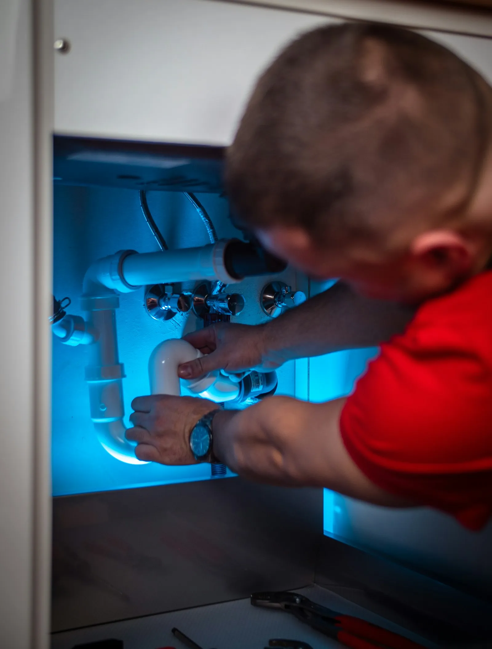 Plumber working on pipes in a sink cabinet