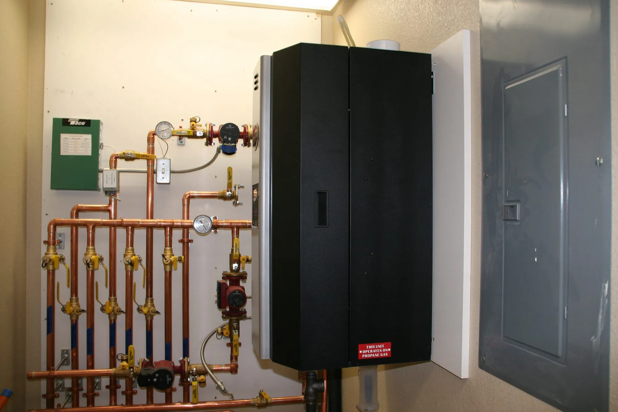 A wall-hung boiler with copper piping and a radiant heating manifold in a mechanical room
