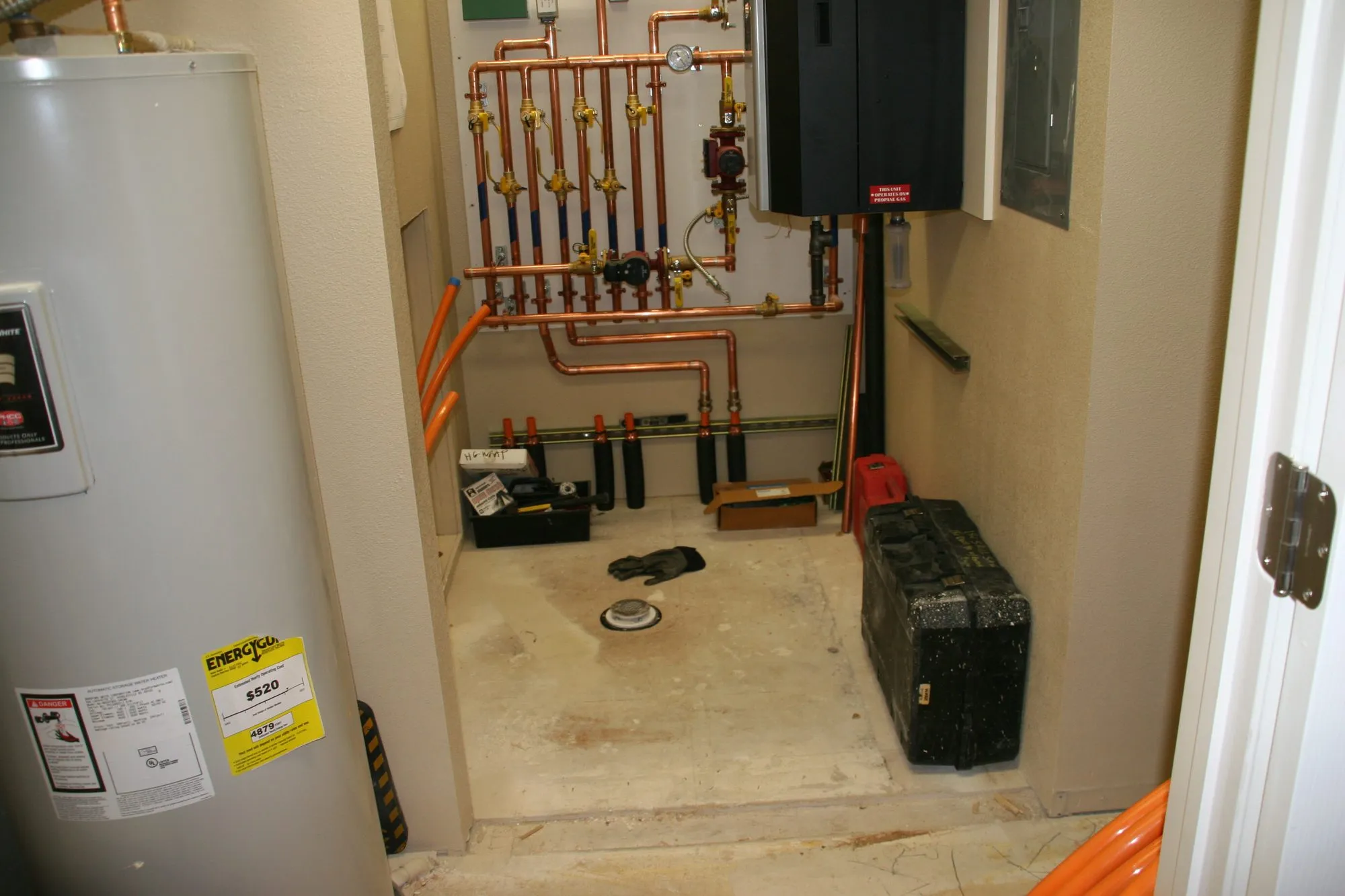 A tank water heater beside copper heating piping in a mechanical room