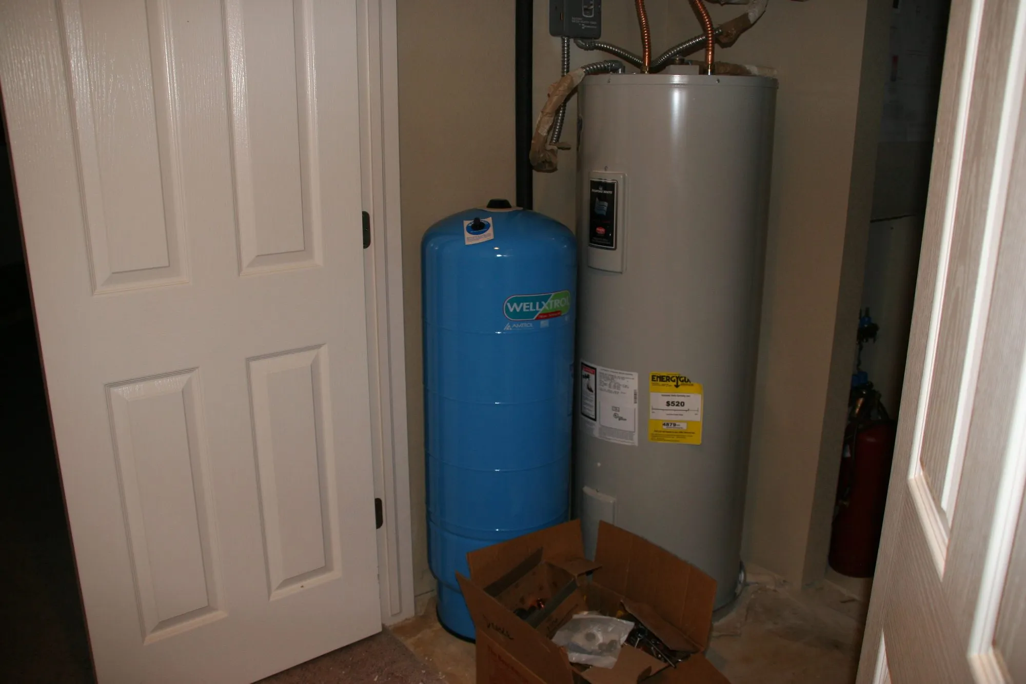 A blue well pressure tank beside a tank water heater